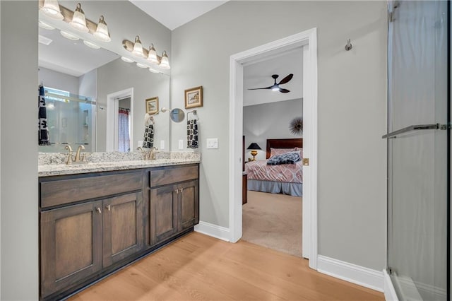 bathroom featuring hardwood / wood-style floors, ceiling fan, a shower with door, and vanity