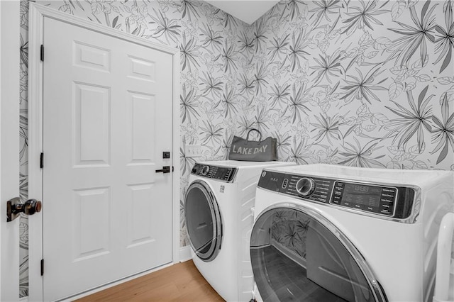 laundry area featuring washing machine and clothes dryer and light wood-type flooring