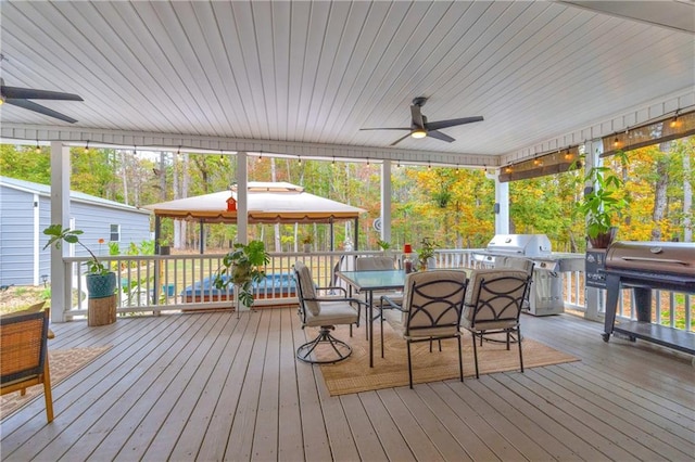 wooden terrace with a gazebo, ceiling fan, and grilling area