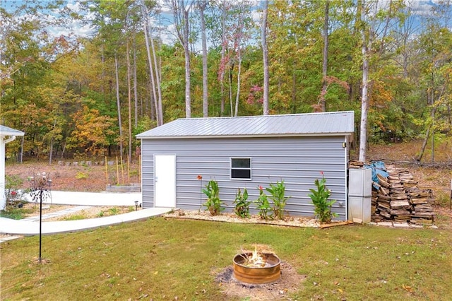 view of outdoor structure with a yard and a fire pit