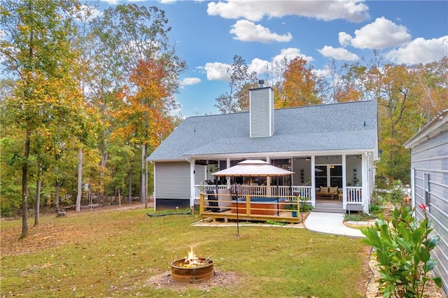 back of house featuring a gazebo, a fire pit, and a lawn