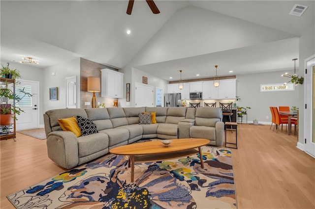 living room featuring light wood-type flooring, high vaulted ceiling, and ceiling fan