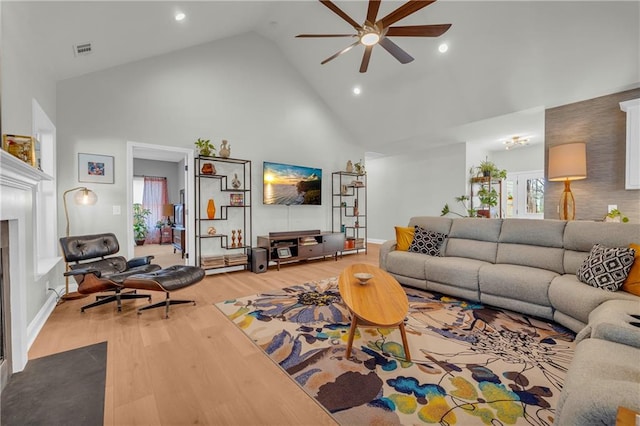 living room with a wealth of natural light, ceiling fan, light hardwood / wood-style flooring, and high vaulted ceiling