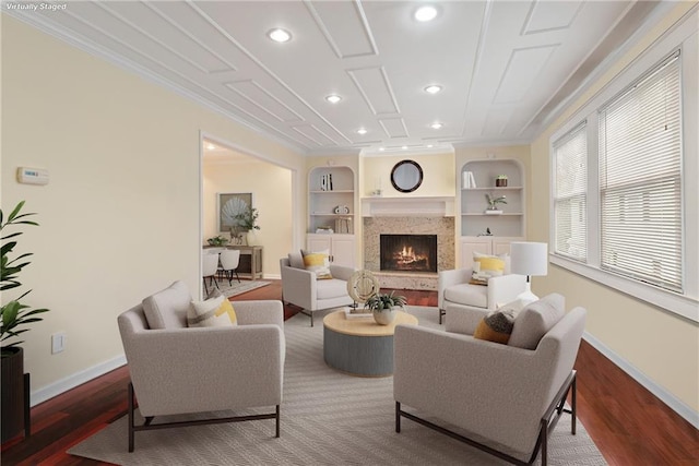 living room with hardwood / wood-style floors, built in features, and a premium fireplace