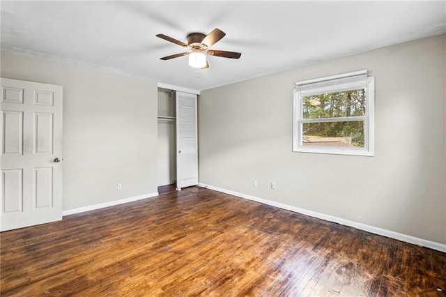 unfurnished bedroom with dark hardwood / wood-style flooring, a closet, and ceiling fan