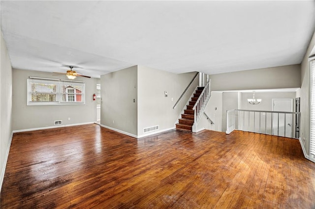 unfurnished living room featuring ceiling fan with notable chandelier and wood-type flooring