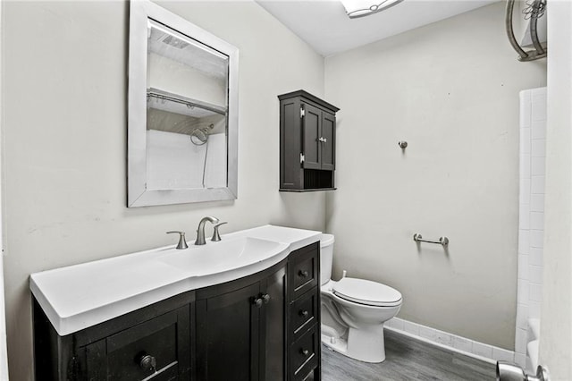 bathroom with hardwood / wood-style floors, vanity, toilet, and a shower