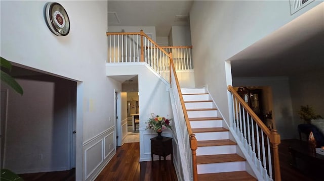 stairs featuring hardwood / wood-style flooring and a high ceiling