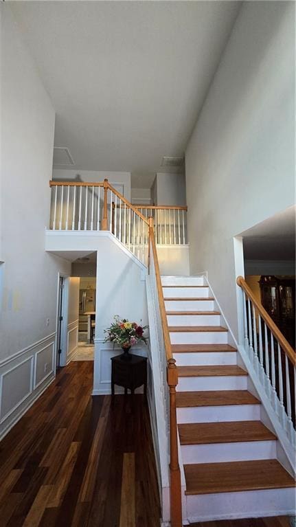 stairs with hardwood / wood-style flooring and a towering ceiling