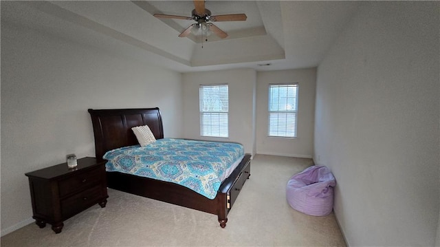 carpeted bedroom with a tray ceiling and ceiling fan