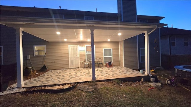 back house at dusk featuring a patio and a trampoline