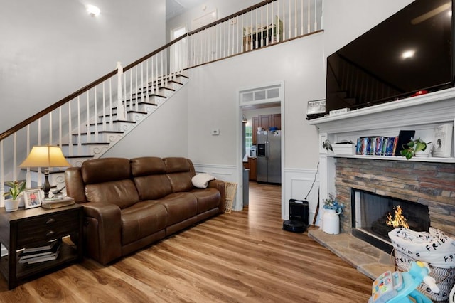 living room with stairway, a fireplace, wood finished floors, and a towering ceiling