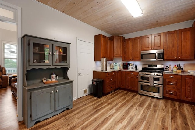 kitchen featuring ornamental molding, light wood finished floors, brown cabinets, and stainless steel appliances