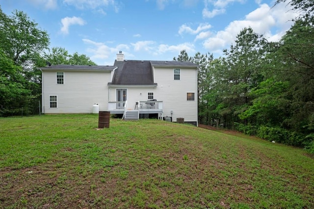 back of house featuring a chimney, a yard, and a deck