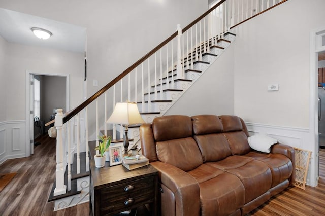 living area with a decorative wall, wood finished floors, stairway, and a wainscoted wall