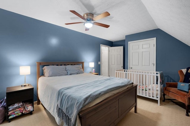 bedroom with a ceiling fan, carpet flooring, a textured ceiling, and lofted ceiling