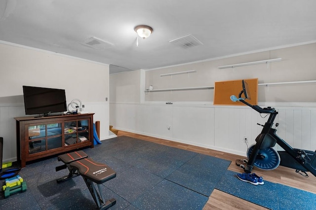 workout area featuring a wainscoted wall, wood finished floors, and visible vents