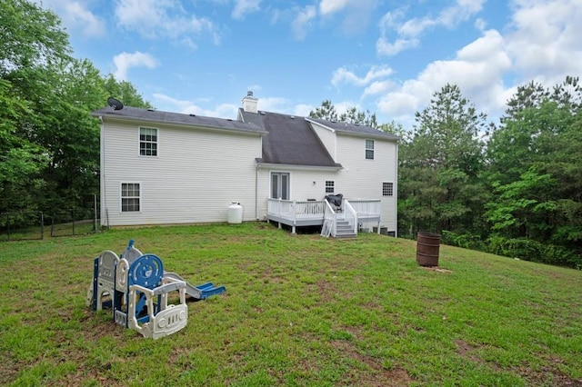 back of property featuring a lawn, fence, a chimney, and a deck