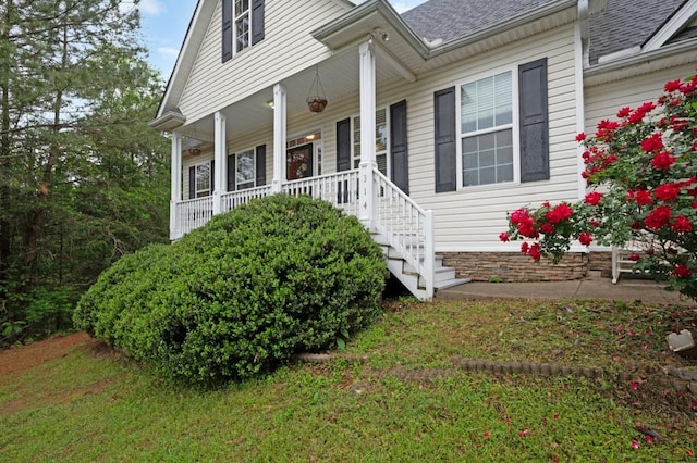 view of front facade featuring covered porch and a shingled roof