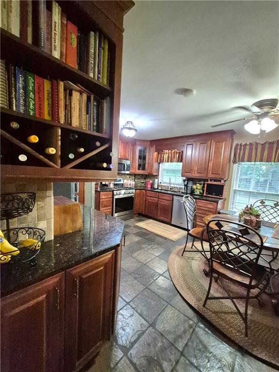 4094 Carlisle Pl, Stone Mountain, GA 30083 - kitchen featuring stainless steel appliances, stone tile flooring, open shelves, a ceiling fan, and dark stone countertops