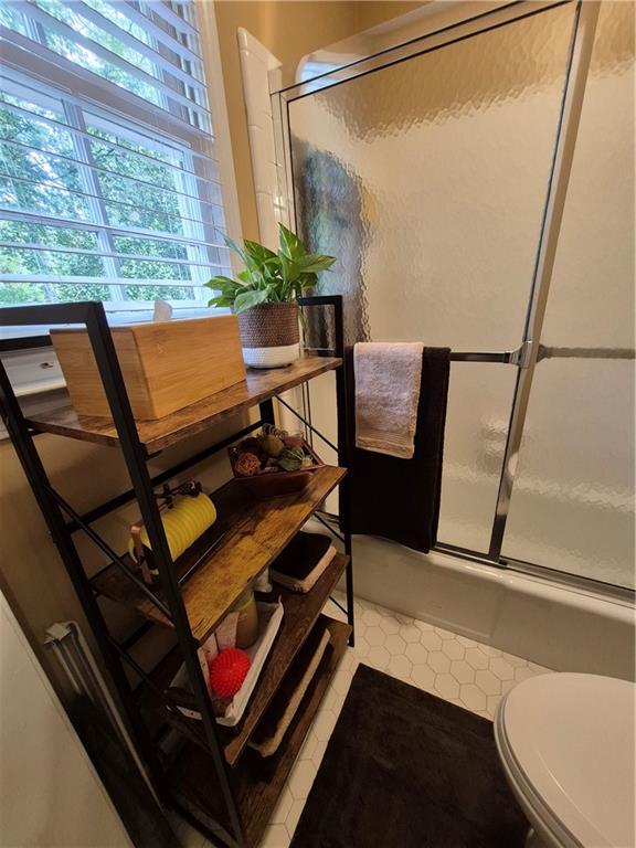 4094 Carlisle Pl, Stone Mountain, GA 30083 - bathroom featuring bath / shower combo with glass door and tile patterned flooring