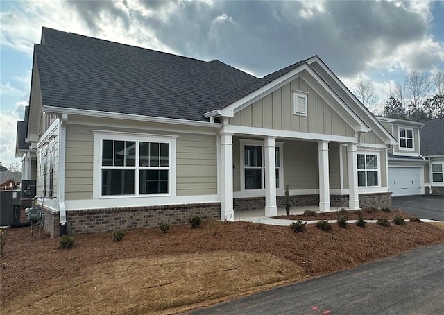 craftsman-style house with a garage, aphalt driveway, roof with shingles, board and batten siding, and a porch