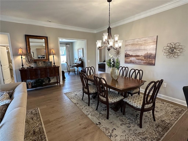 dining area with baseboards, ornamental molding, wood finished floors, and a notable chandelier