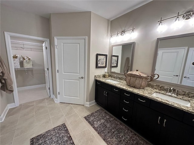 full bathroom with double vanity, a sink, baseboards, and a spacious closet