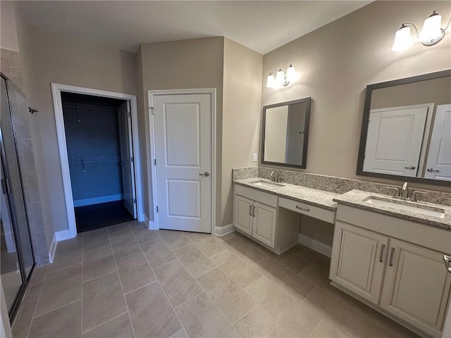 bathroom featuring double vanity, a sink, a walk in closet, and a stall shower