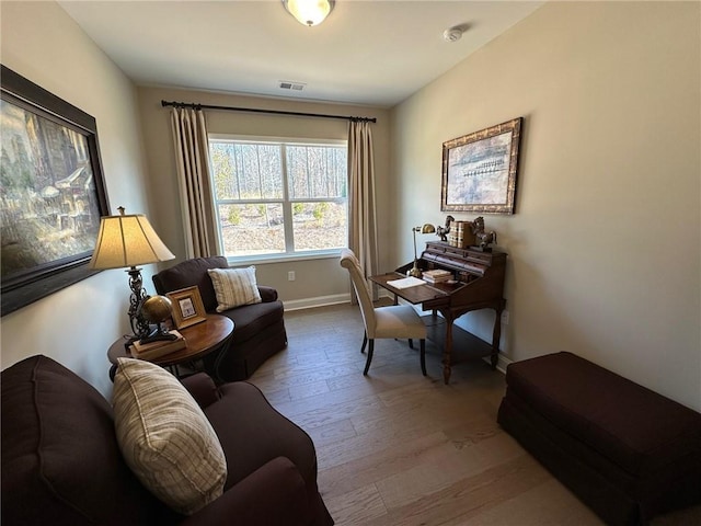 living area featuring visible vents, baseboards, and wood finished floors