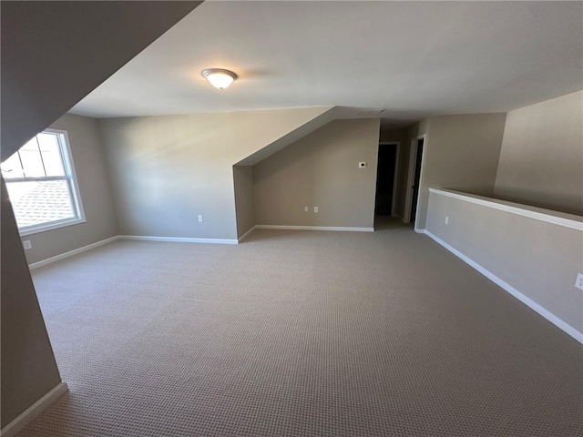 additional living space with baseboards and light carpet
