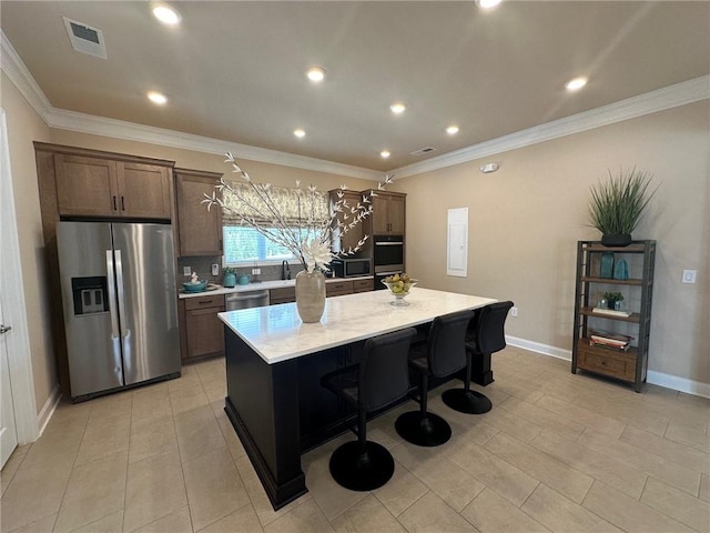 kitchen featuring a kitchen breakfast bar, visible vents, a center island, baseboards, and stainless steel appliances