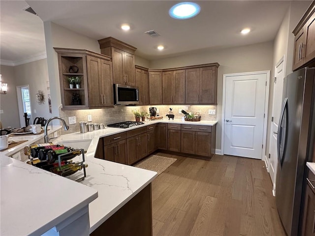 kitchen with visible vents, open shelves, light stone counters, a peninsula, and stainless steel appliances