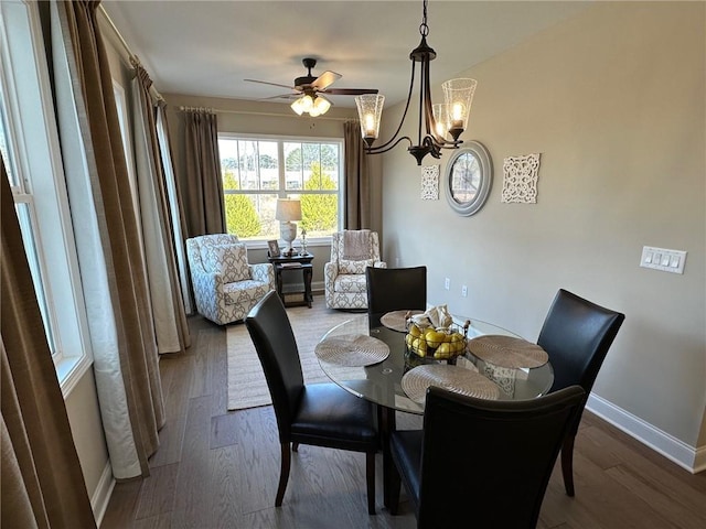 dining space featuring baseboards, ceiling fan with notable chandelier, and wood finished floors