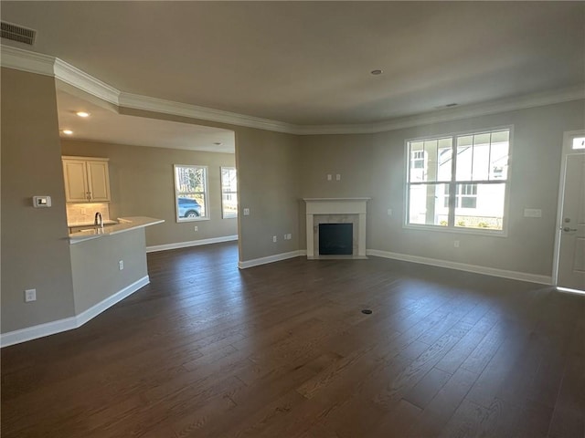 unfurnished living room with visible vents, crown molding, dark wood-style flooring, baseboards, and a high end fireplace