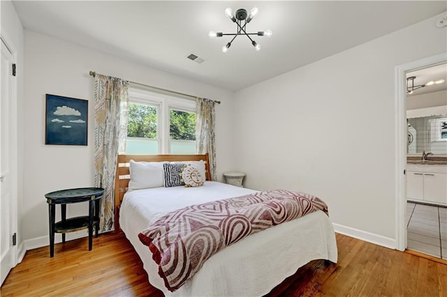 1544 Brewer Blvd SW, Atlanta, GA 30310 - bedroom with a chandelier, light wood-style floors, baseboards, a sink, and ensuite bathroom