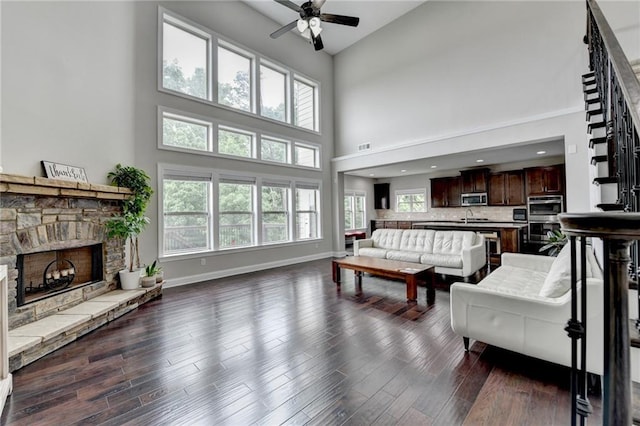 5770 Bridleton Xing, Suwanee, GA 30024 - living room featuring high vaulted ceiling, a ceiling fan, a stone fireplace, baseboards, and dark wood finished floors