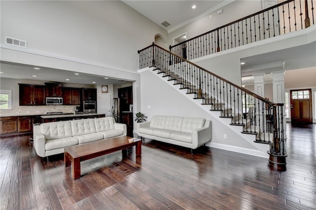 5770 Bridleton Xing, Suwanee, GA 30024 - living area featuring a towering ceiling, dark wood-style flooring, stairs, baseboards, and ornate columns