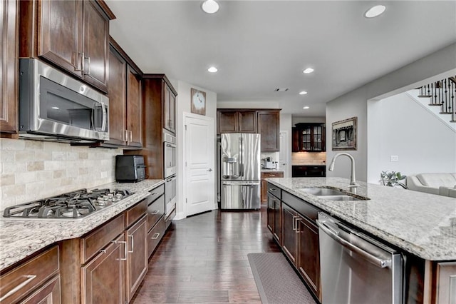 5770 Bridleton Xing, Suwanee, GA 30024 - kitchen featuring stainless steel appliances, a sink, an island with sink, light stone countertops, and dark wood-type flooring