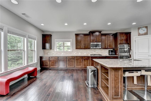 5770 Bridleton Xing, Suwanee, GA 30024 - kitchen featuring appliances with stainless steel finishes, a sink, light stone counters, backsplash, and dark wood-style flooring