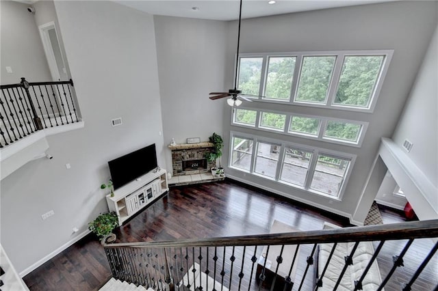 5770 Bridleton Xing, Suwanee, GA 30024 - living room featuring a fireplace, a high ceiling, ceiling fan, wood finished floors, and baseboards