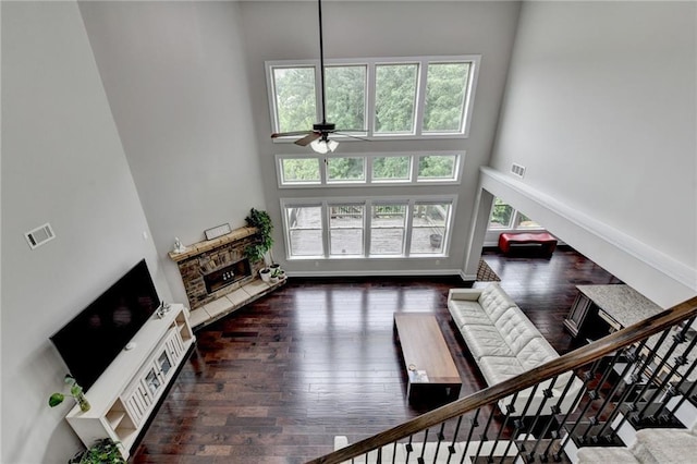 5770 Bridleton Xing, Suwanee, GA 30024 - living area featuring a towering ceiling, a ceiling fan, a stone fireplace, wood-type flooring, and baseboards