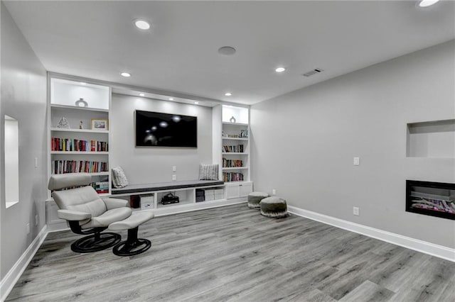 5770 Bridleton Xing, Suwanee, GA 30024 - living area featuring wood finished floors, built in features, recessed lighting, a glass covered fireplace, and baseboards
