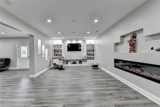 5770 Bridleton Xing, Suwanee, GA 30024 - living room with recessed lighting, baseboards, wood finished floors, built in features, and a glass covered fireplace