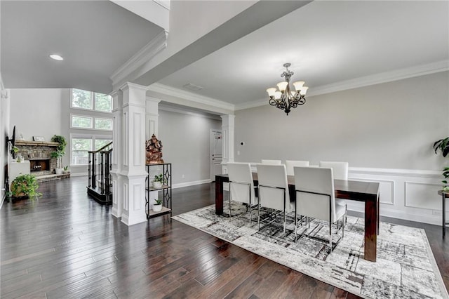 5770 Bridleton Xing, Suwanee, GA 30024 - dining space with ornate columns, crown molding, a chandelier, a fireplace, and dark wood-style flooring