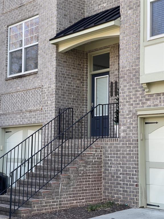 doorway to property featuring brick siding and a garage