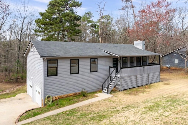 view of front of property featuring a chimney, stairway, a garage, driveway, and a front lawn