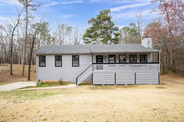 view of front facade featuring covered porch, a front lawn, a chimney, and stairs