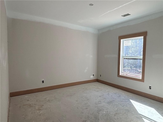 empty room featuring unfinished concrete floors, visible vents, and baseboards