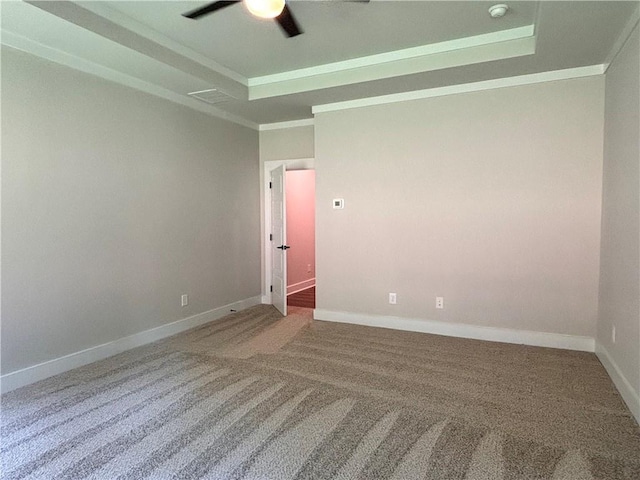 empty room with ornamental molding, a tray ceiling, and carpet